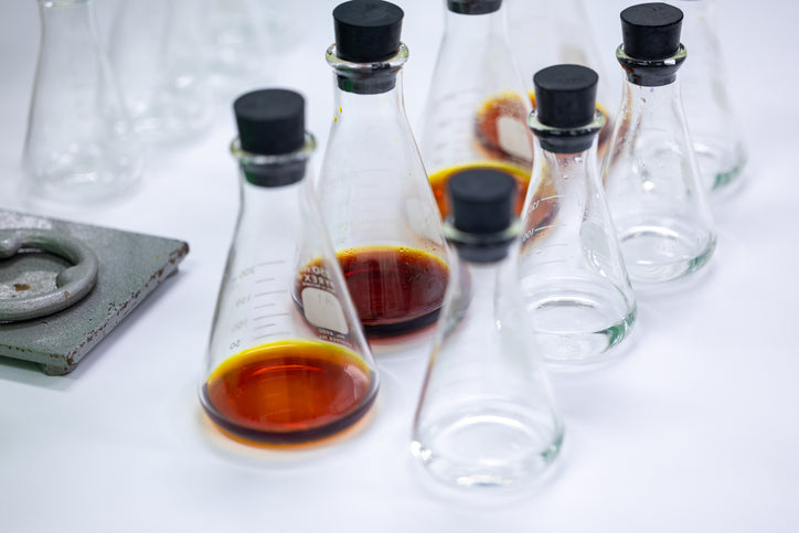 Set of glass flasks with raw material liquid on a white surface